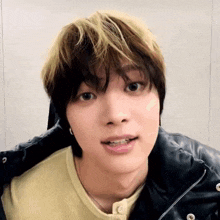 a close up of a person 's face with a yellow shirt and black jacket