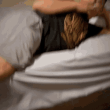 a blurry picture of a person laying on a bed with a black shirt on