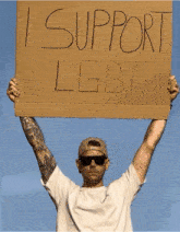 a man holding up a sign that says i support lgbt