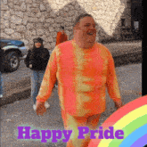 a man in a tie dye shirt is standing in front of a stone wall with the words happy pride above him