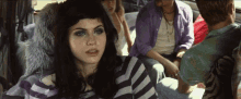 a woman in a striped shirt sits in the back seat of a car