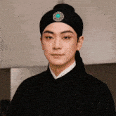a man wearing a black turban with a turquoise circle on top