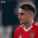 a man wearing a red adidas jersey with three stars on the front