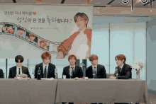a group of people sitting at a table with a sign behind them that says ' i love you ' on it