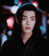 a man with long hair and a ponytail looks at the camera