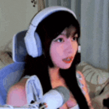 a woman wearing headphones and holding a microphone is sitting in a chair .