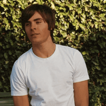 a man in a white t-shirt is sitting on a bench