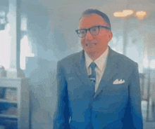 a man in a suit and tie is standing in a room and making a funny face .