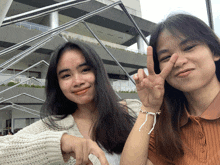 two young women are posing for a picture and one is giving the peace sign