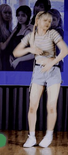 a woman in shorts and a striped shirt is dancing on a stage