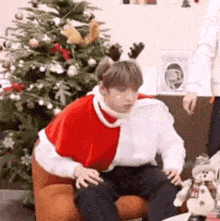 a man is sitting in a chair in front of a christmas tree .