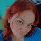 a woman with red hair is wearing a blue shirt and looking at the camera