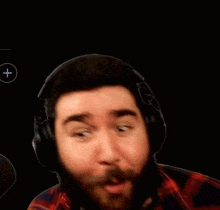 a man with a beard wearing headphones is making a surprised face .
