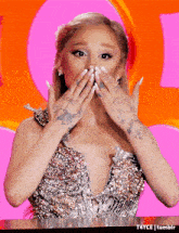 ariana grande is wearing a sequined dress and covering her mouth with her hands