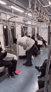 a man is bending over in a subway car while a woman looks on .