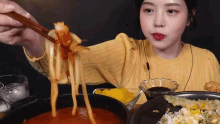a woman is eating noodles with chopsticks and a bowl of food .