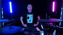 a man in a black shirt with the letter h on it is playing drums