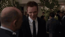 a man in a suit and tie talks to another man