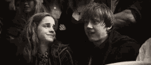 a man and a woman are sitting next to each other in a crowd of people .