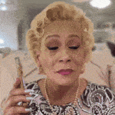 a woman looking at herself in a mirror while wearing a pearl necklace