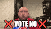 a bald man is holding a bag of chips and says vote no