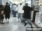 a group of people are dancing in a hallway with a make a gif.com link in the bottom right corner .