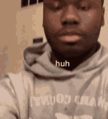 a man in a gray hoodie is taking a selfie with his mouth open .