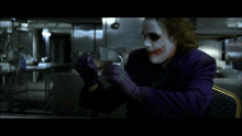 a man dressed as the joker is sitting in a chair with his arms outstretched