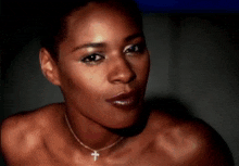 a woman wearing a cross necklace looks at the camera
