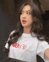 a woman wearing a white t-shirt with a red lettering that says " a "