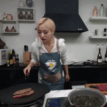 a woman wearing an apron with a daisy on it is cooking in a kitchen