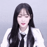 a woman with long black hair wearing a white shirt and black tie