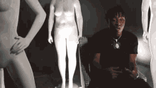 a man is sitting in a chair in front of a group of naked women .