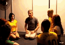 a group of people are sitting in a circle with one wearing a ronaldinho shirt