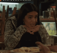a woman sitting at a table with a plate of food and a glass of beer .