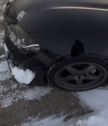 a black car is covered in snow and has a tire that says continental