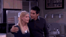 a man and a woman are hugging in front of a refrigerator