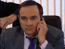 a man in a suit and tie is talking on a phone