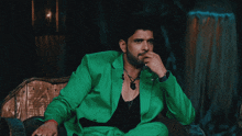 a man in a green suit is sitting on a chair