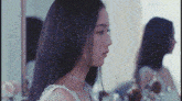 a woman in a white dress is looking at herself in a mirror .