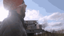 a man wearing a hard hat and sunglasses looks at a building in the distance