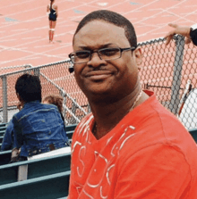 a man wearing glasses and a red shirt that says ' uc ' on it