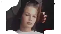 a woman is brushing her hair and looking at the camera while wearing a white shirt .