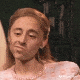 a woman in a pink dress is making a funny face and looking at the camera .