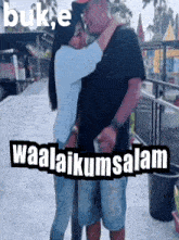 a woman kisses a man on the cheek in front of a sign that says waalaikussalam