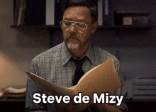 a man holding a piece of paper with the name steve de mizy above him