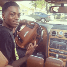a young man is driving a bentley car
