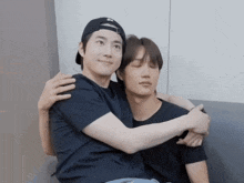 two men are hugging each other with one wearing a black hat