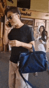 a man is talking on a cell phone while carrying a blue bag