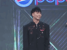 a man is standing with his arms in the air in front of a pepsi logo .